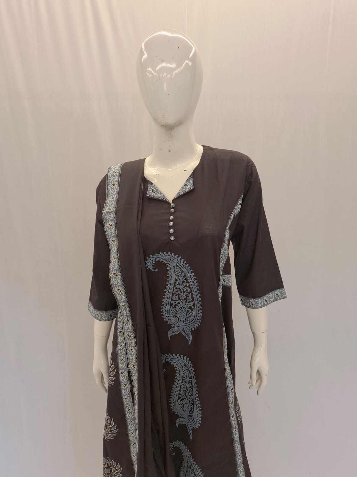 Brown dress with paisley patterns on a mannequin against a plain background