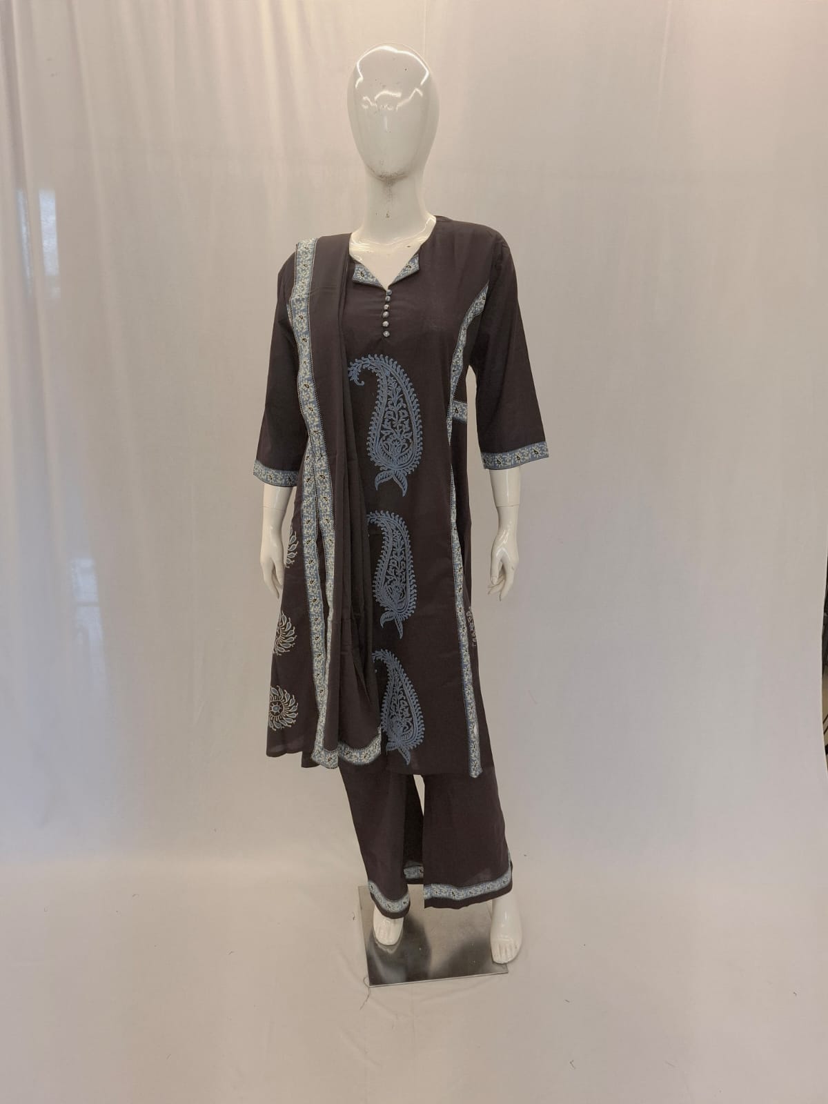 Mannequin wearing a brown outfit with lace details on a white background