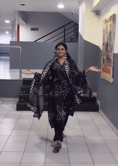 Woman posing in a stylish outfit with butterfly patterns in an indoor setting.