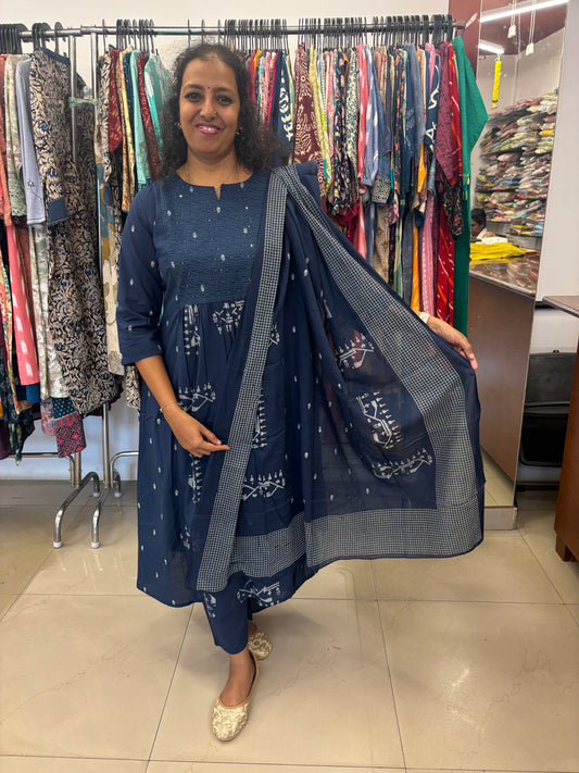 Woman holding a blue saree with patterns in a store setting