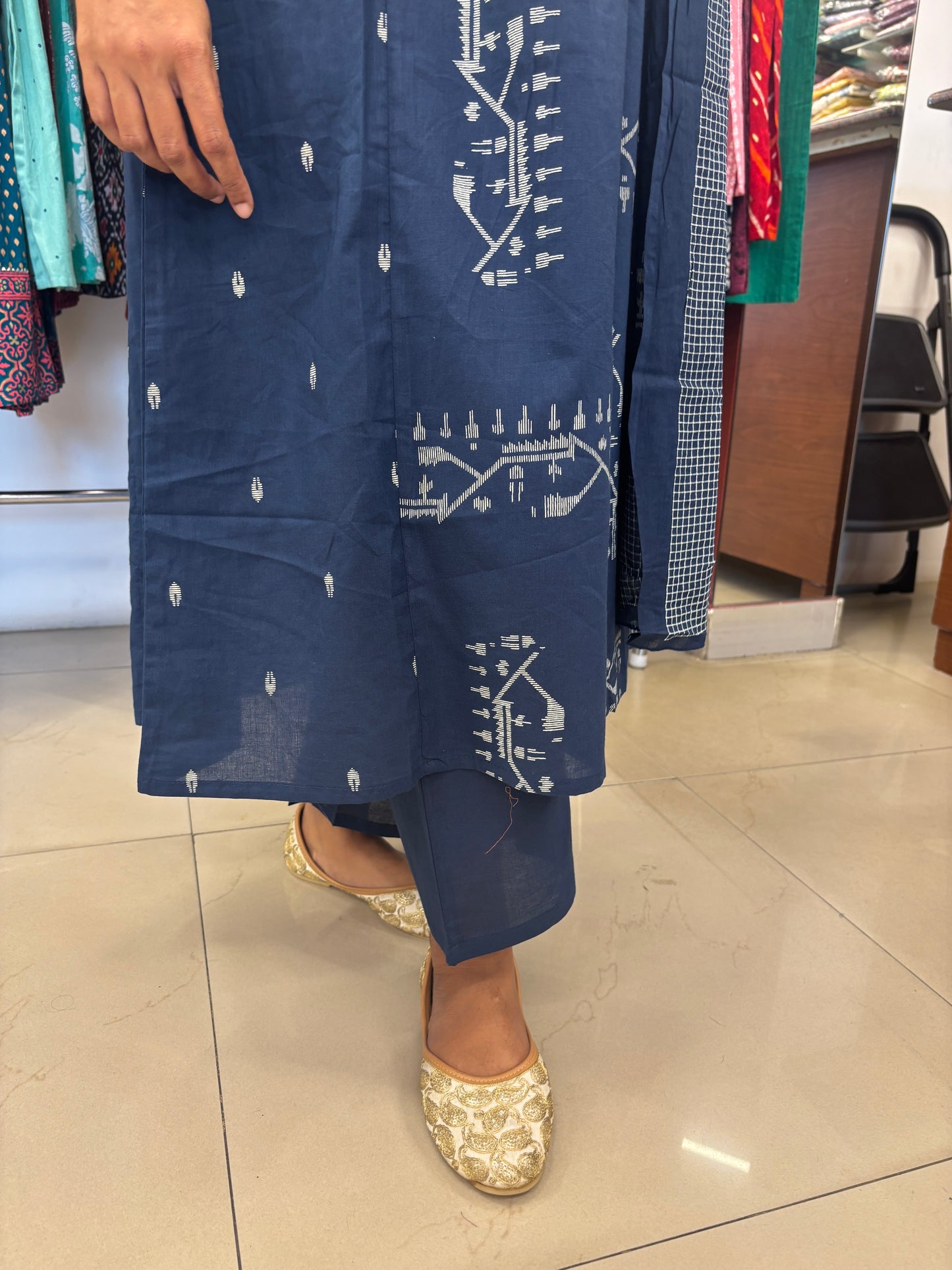 Person holding a folded blue fabric with white patterns on a tiled floor.