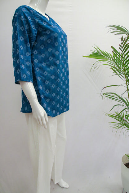 Mannequin wearing a blue patterned top with white pants against a plain background