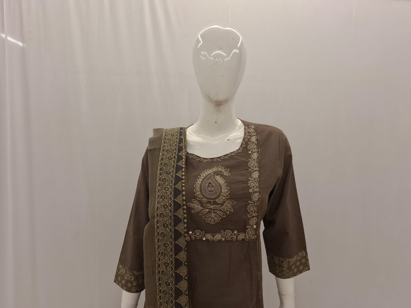 Brown embroidered top on a mannequin against a plain background