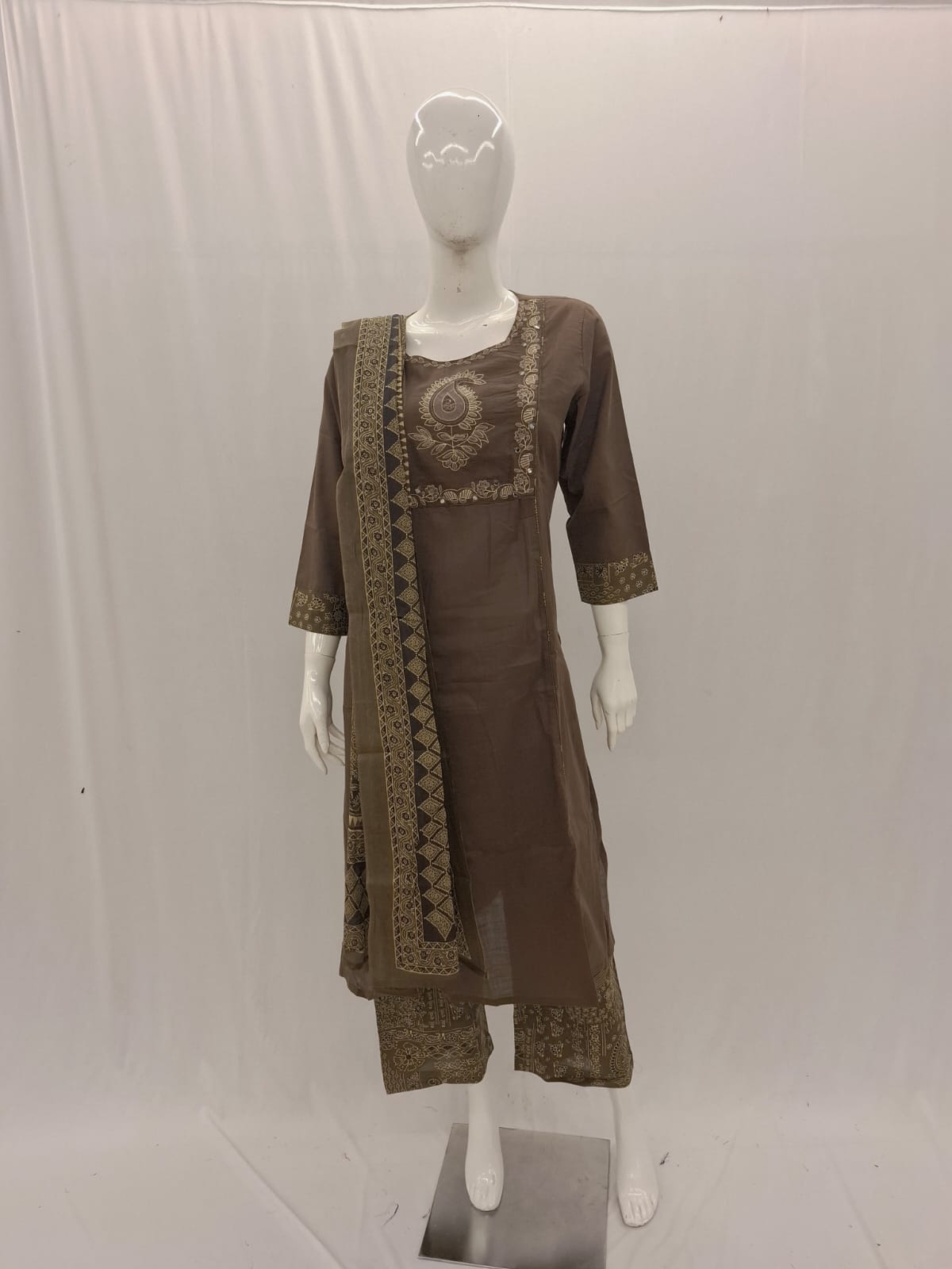 Brown traditional outfit with embroidered details on a mannequin against a white background