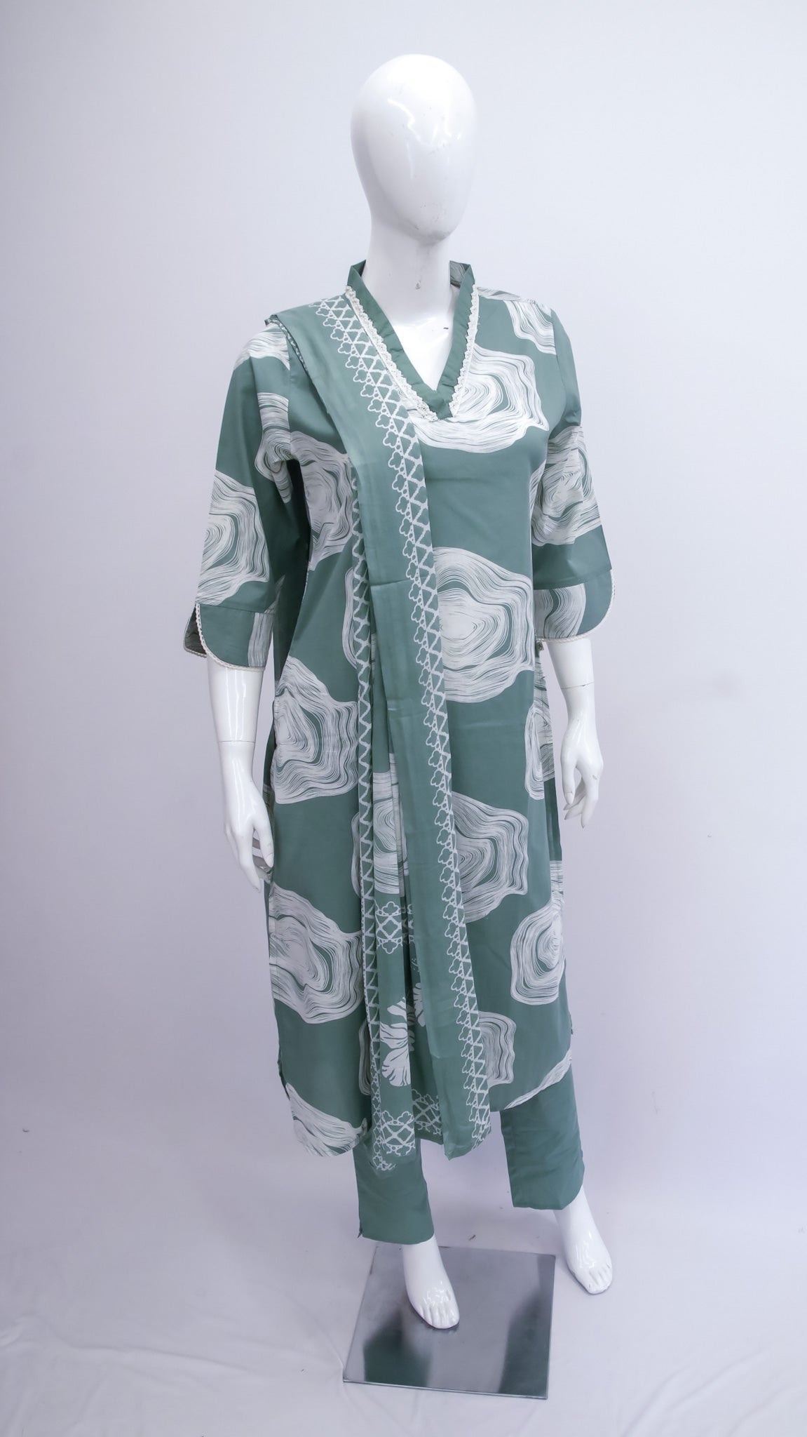Green and white patterned dress on a mannequin against a white background