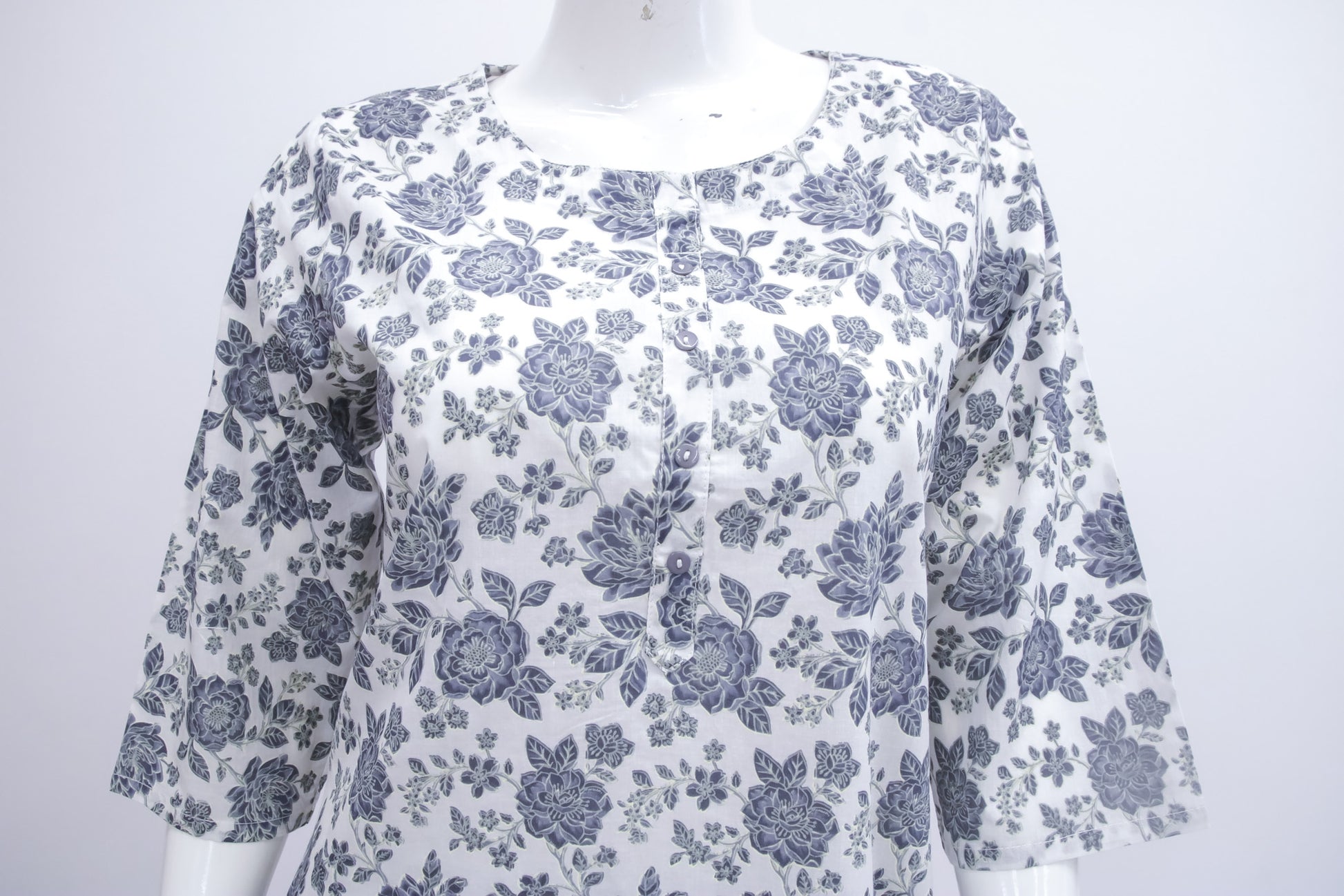 White blouse with blue floral pattern on a mannequin against a white background