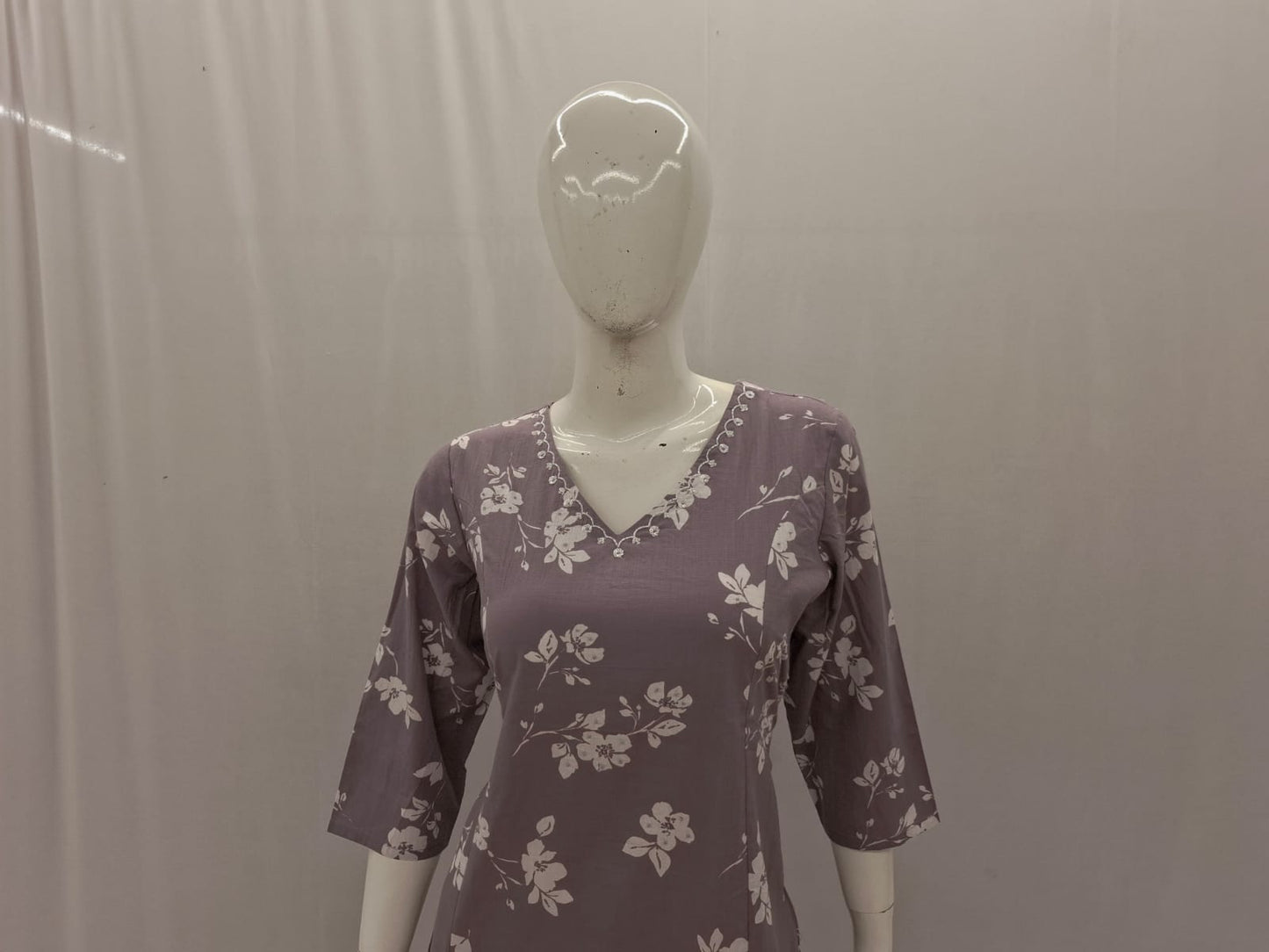 Mannequin wearing a purple floral dress against a plain background
