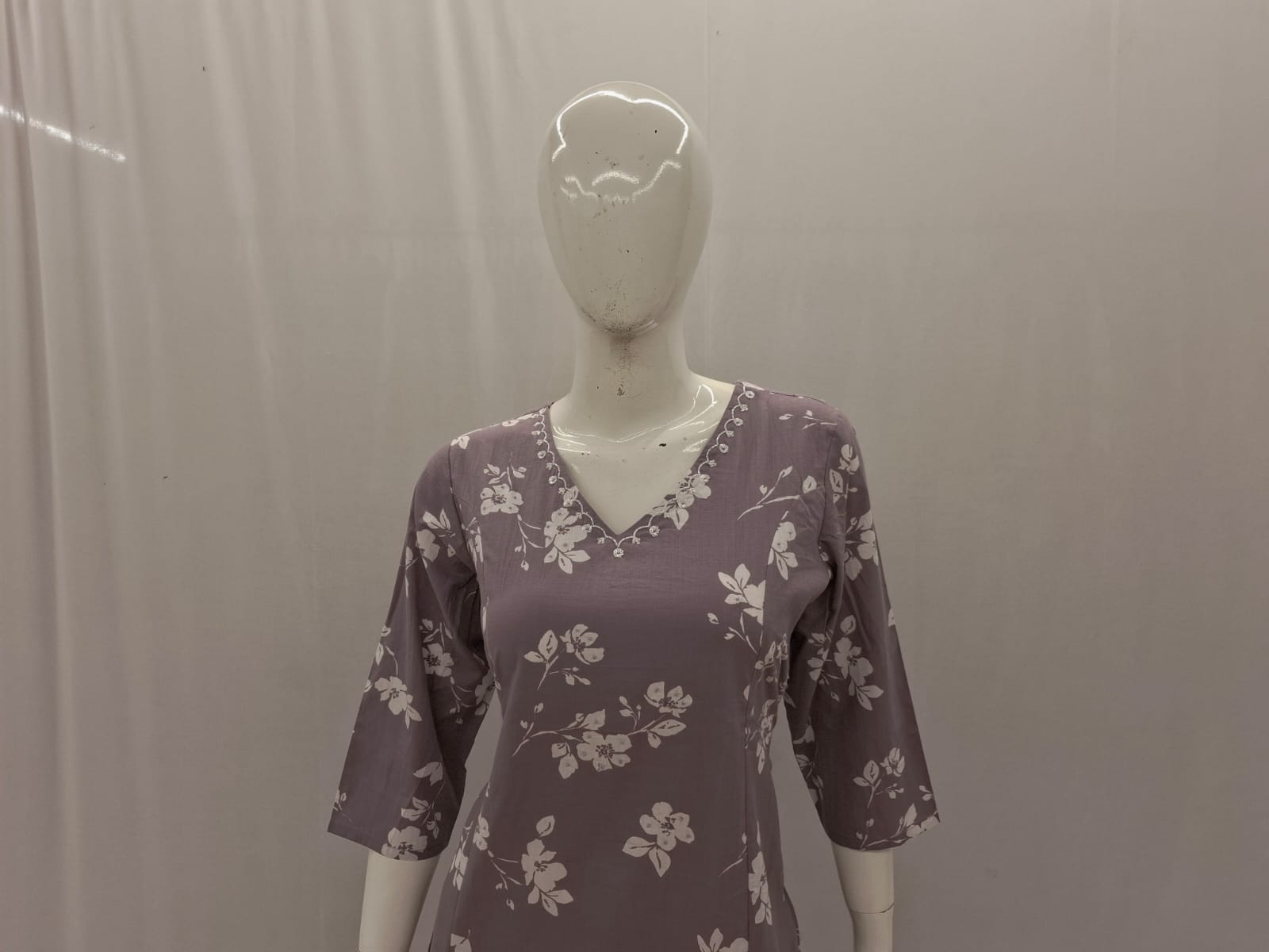 Mannequin wearing a purple floral dress against a plain background
