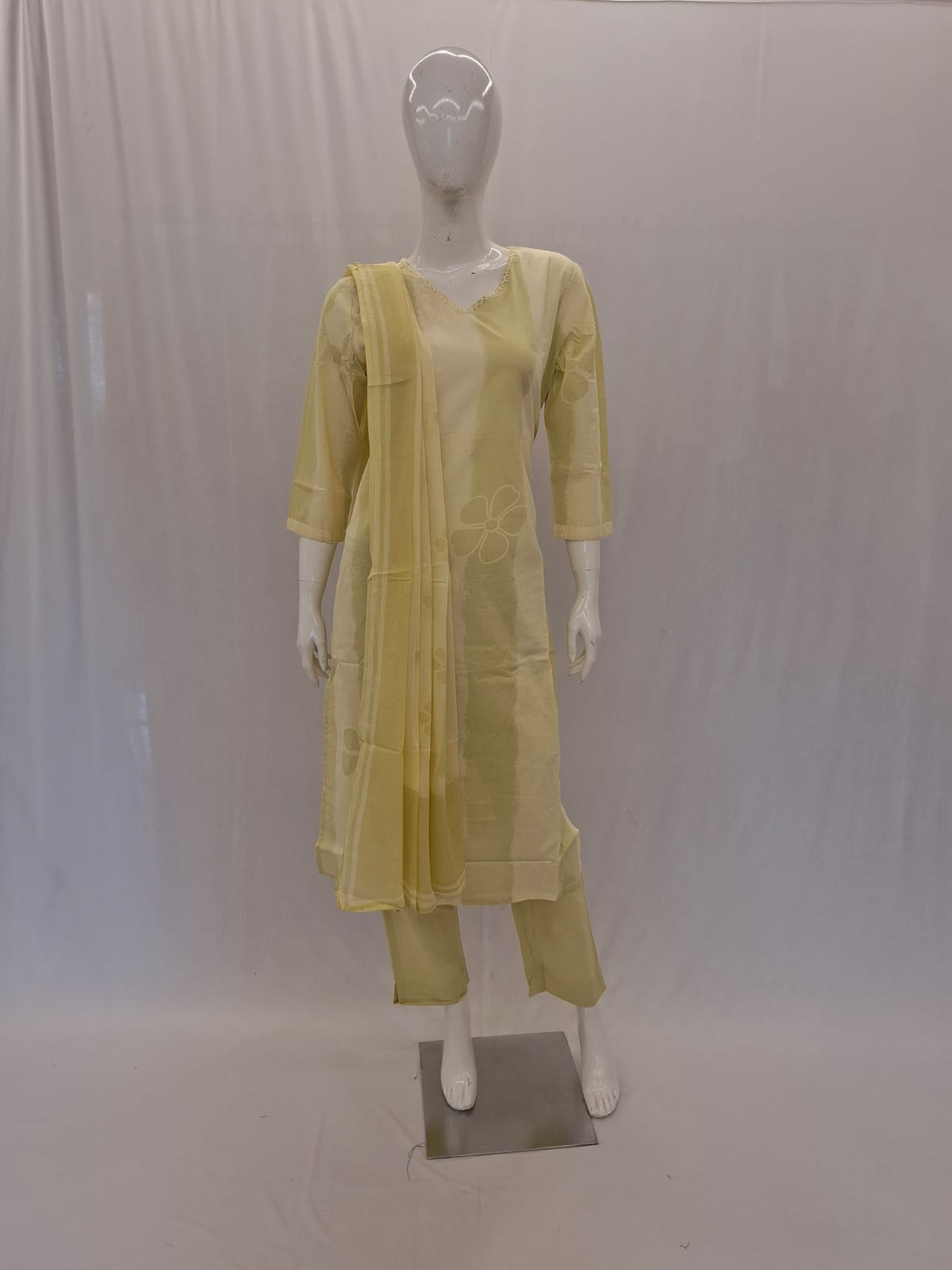 Mannequin wearing a light yellow traditional outfit with a sheer dupatta against a plain background