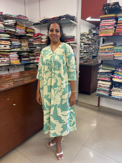 Woman in a green floral dress standing in a fabric store.