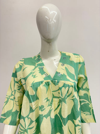Mannequin wearing a green and white floral dress on a plain background