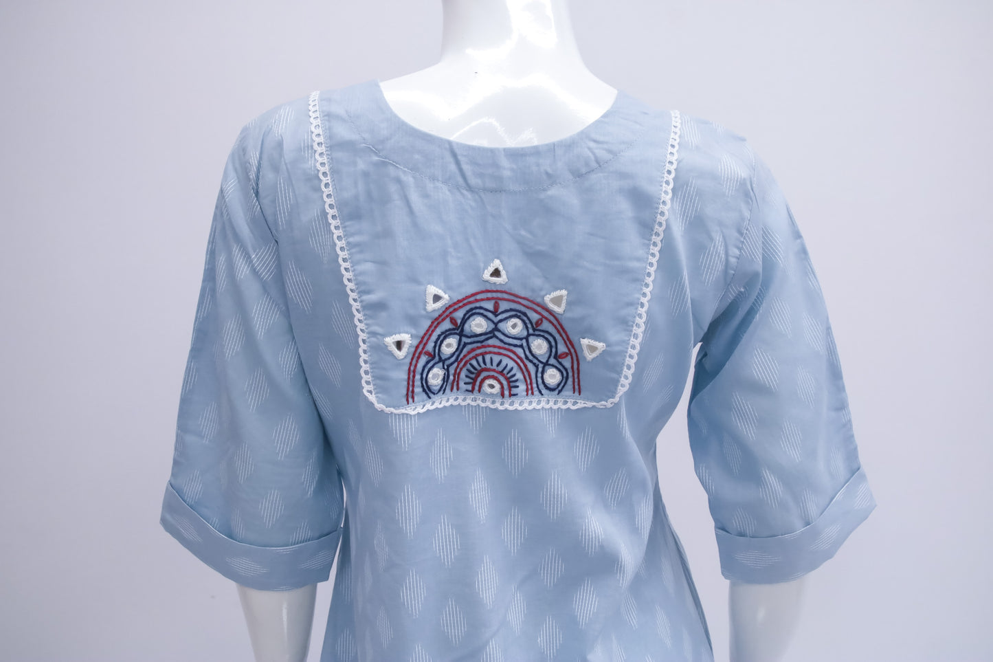Light blue blouse with embroidered design on a mannequin against a white background