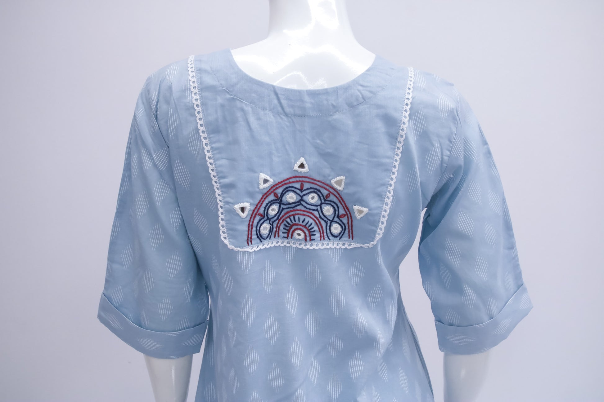 Light blue blouse with embroidered design on a mannequin against a white background