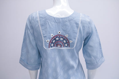 Light blue blouse with embroidered design on a mannequin against a white background