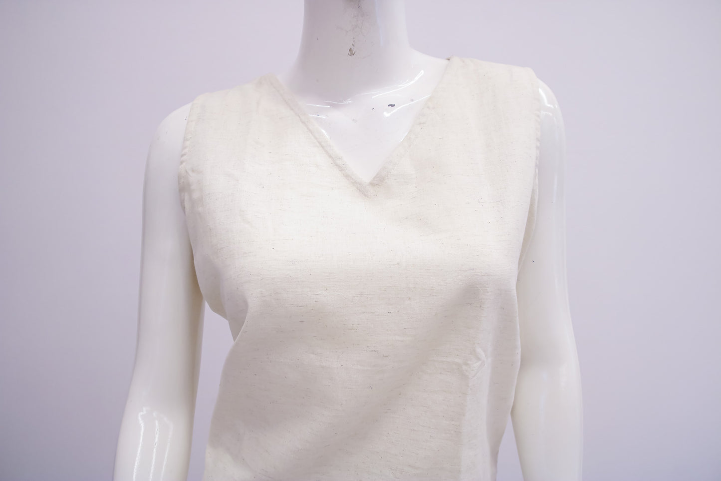 White sleeveless sweater on a mannequin against a white background