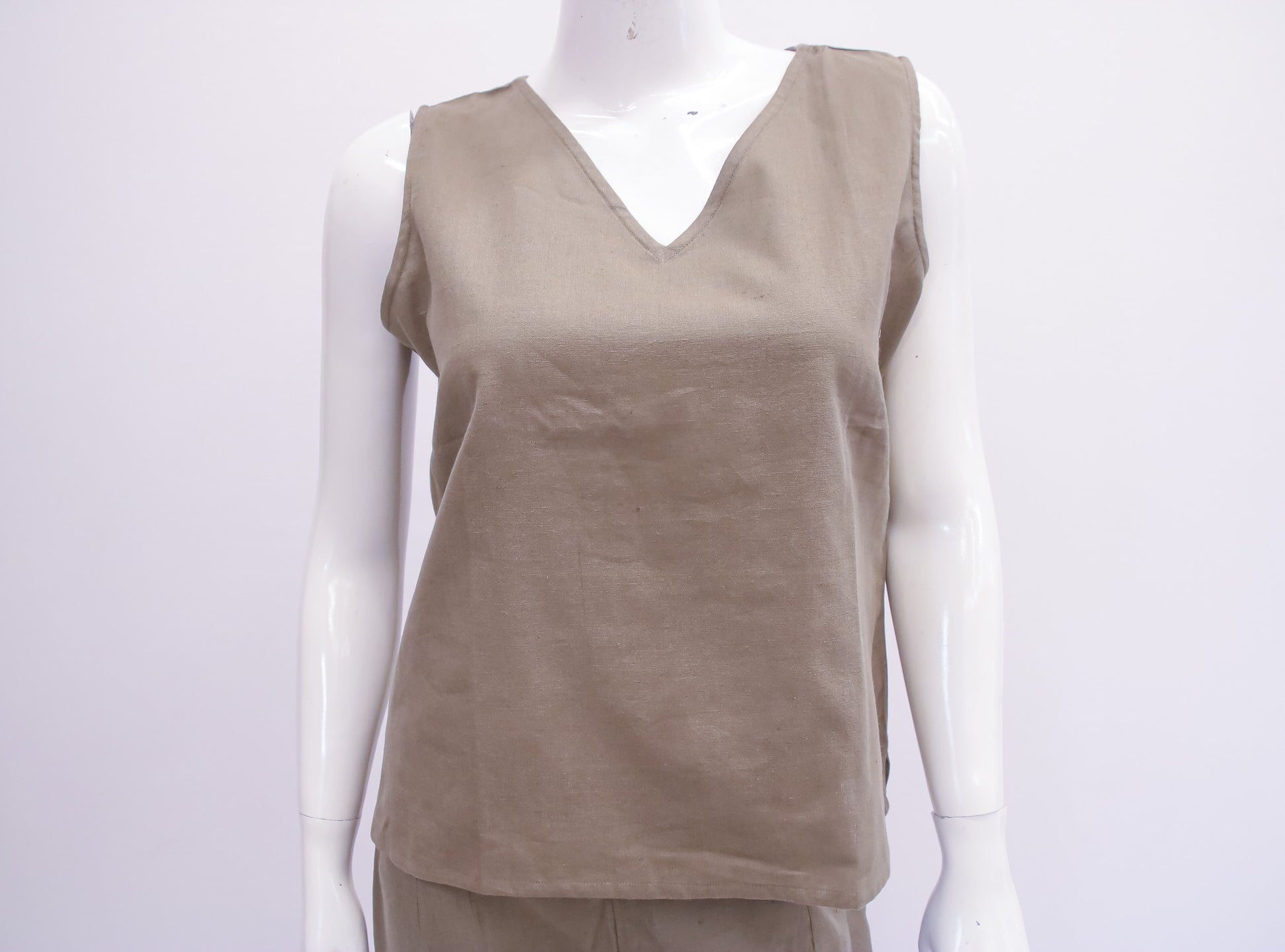Beige sleeveless top on a mannequin against a white background