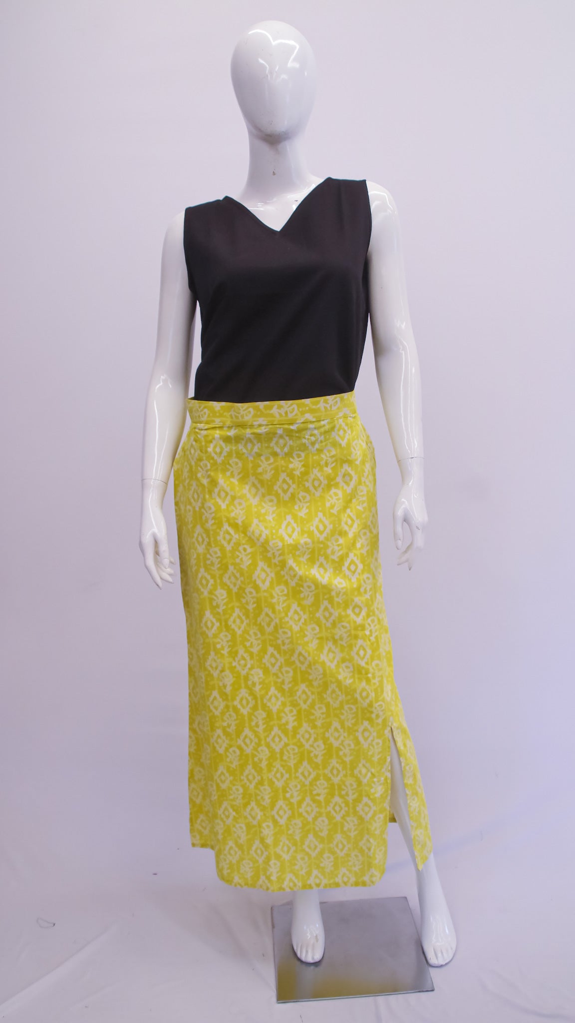 Mannequin wearing a black top and yellow patterned skirt on a white background