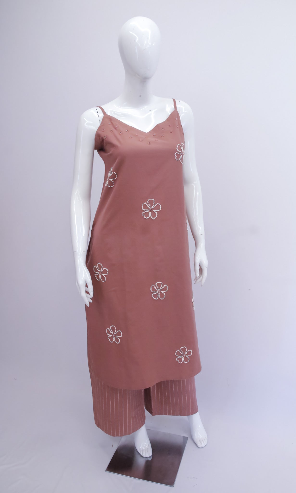 Brown dress with floral patterns on a mannequin against a gray background
