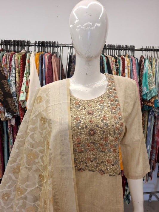 Mannequin wearing a beige outfit with floral blouse in a clothing store setting