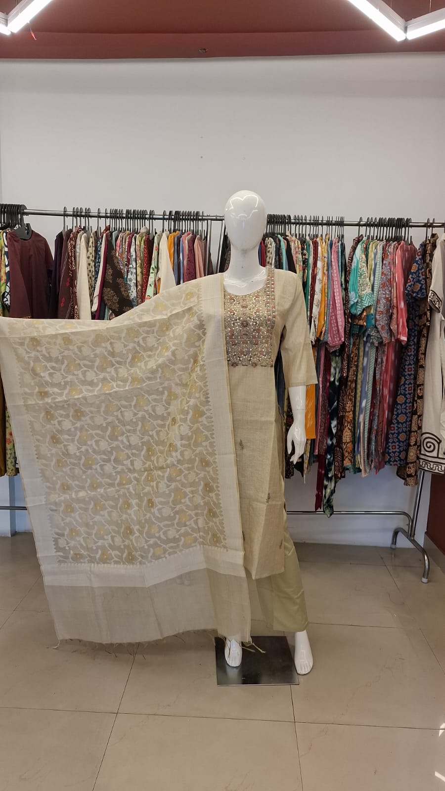 Mannequin wearing a traditional outfit with a floral shawl in a clothing store.