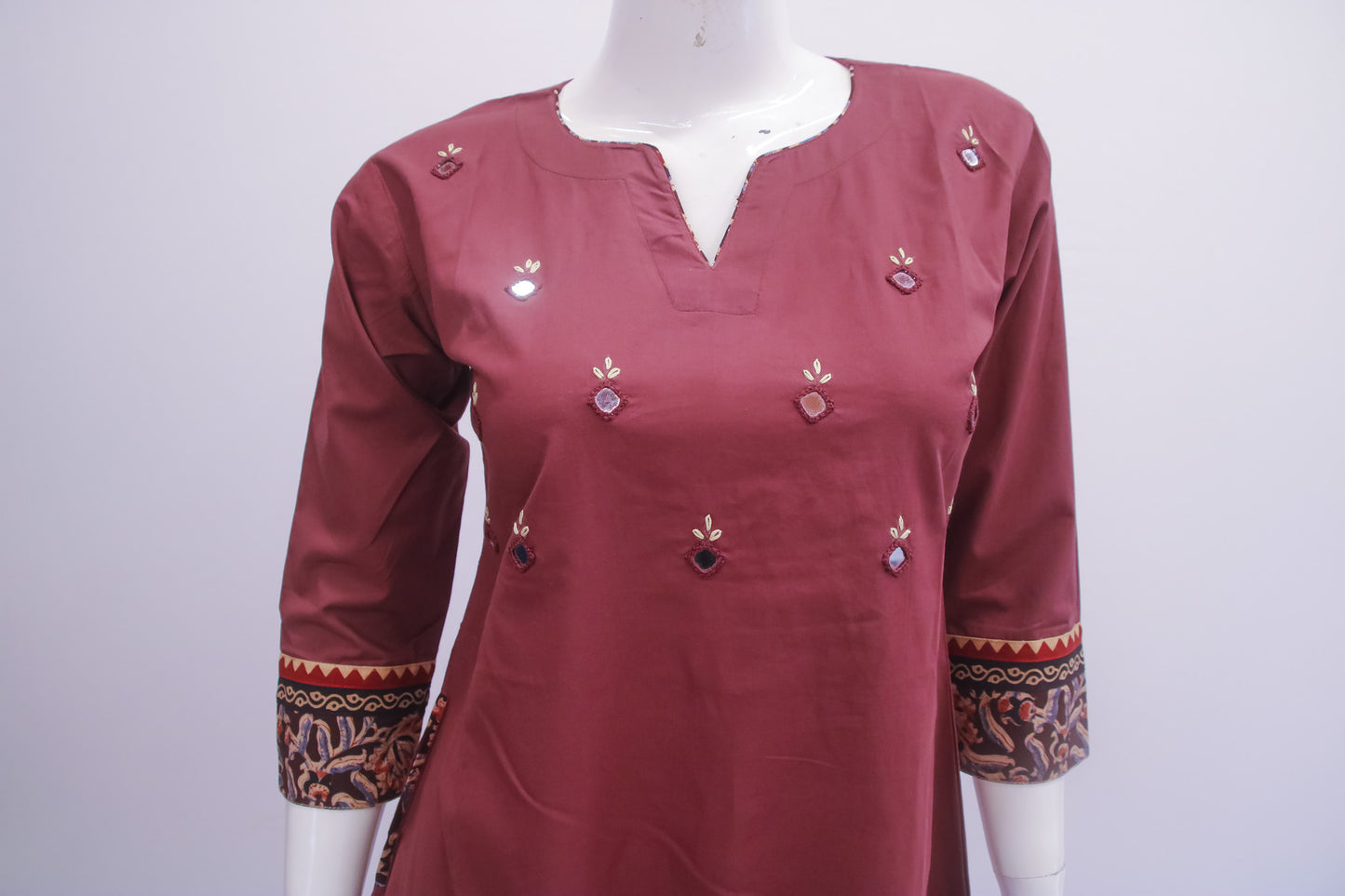 Maroon kurta with decorative patterns on a mannequin against a white background