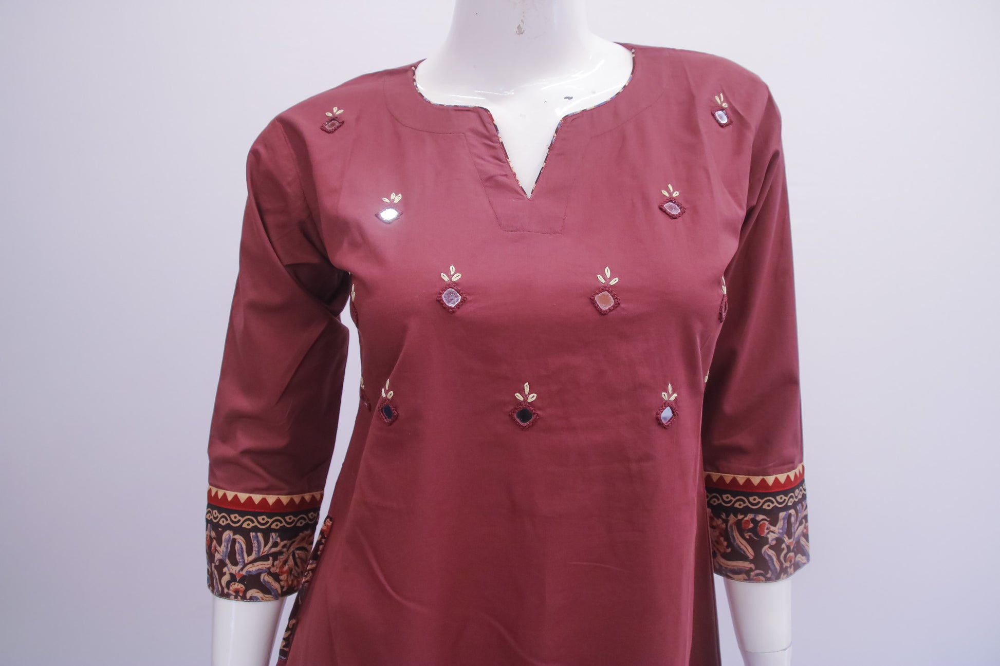 Maroon kurta with decorative patterns on a mannequin against a white background
