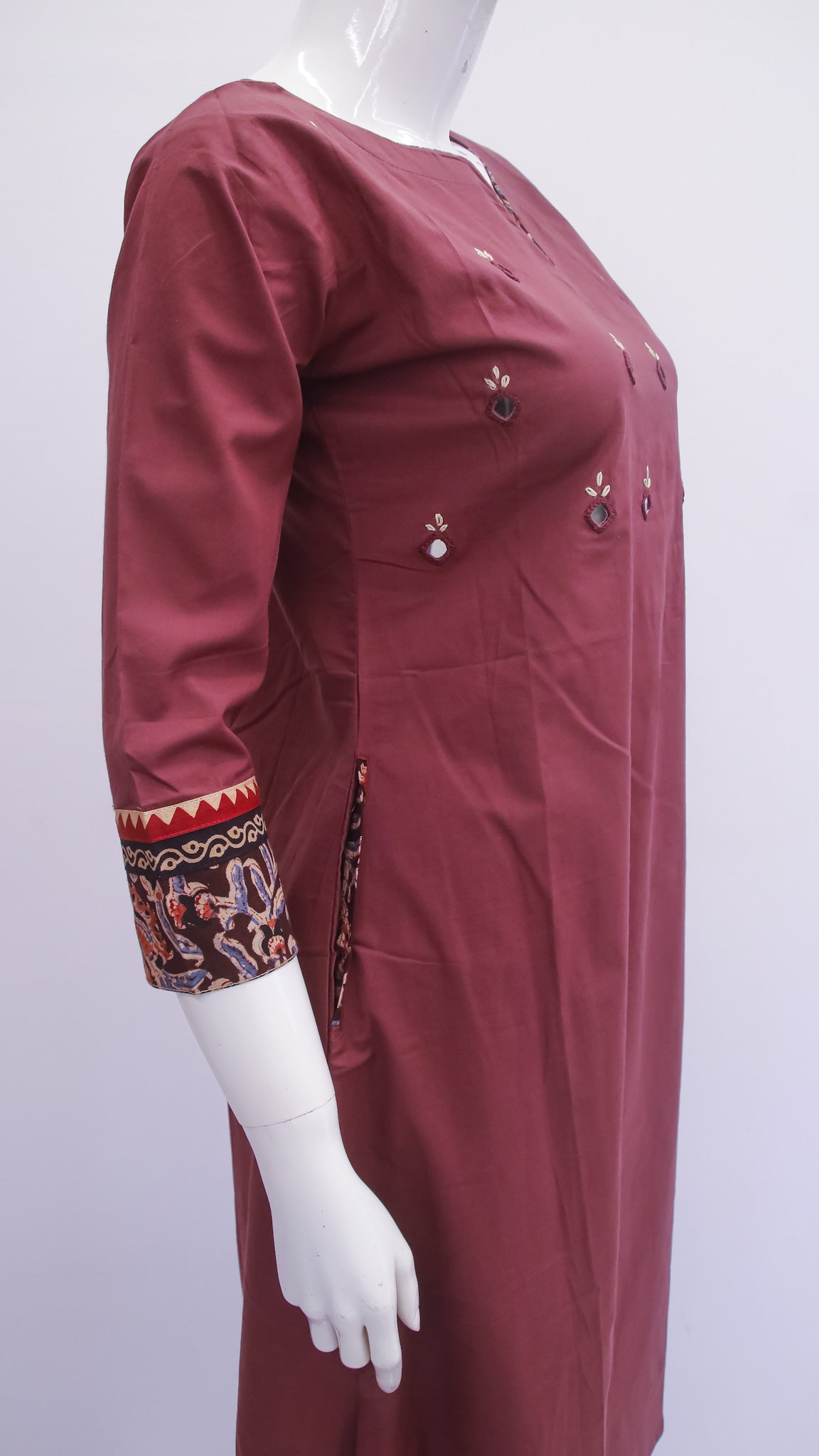 Maroon dress with intricate patterns on sleeves displayed on a mannequin against a white background