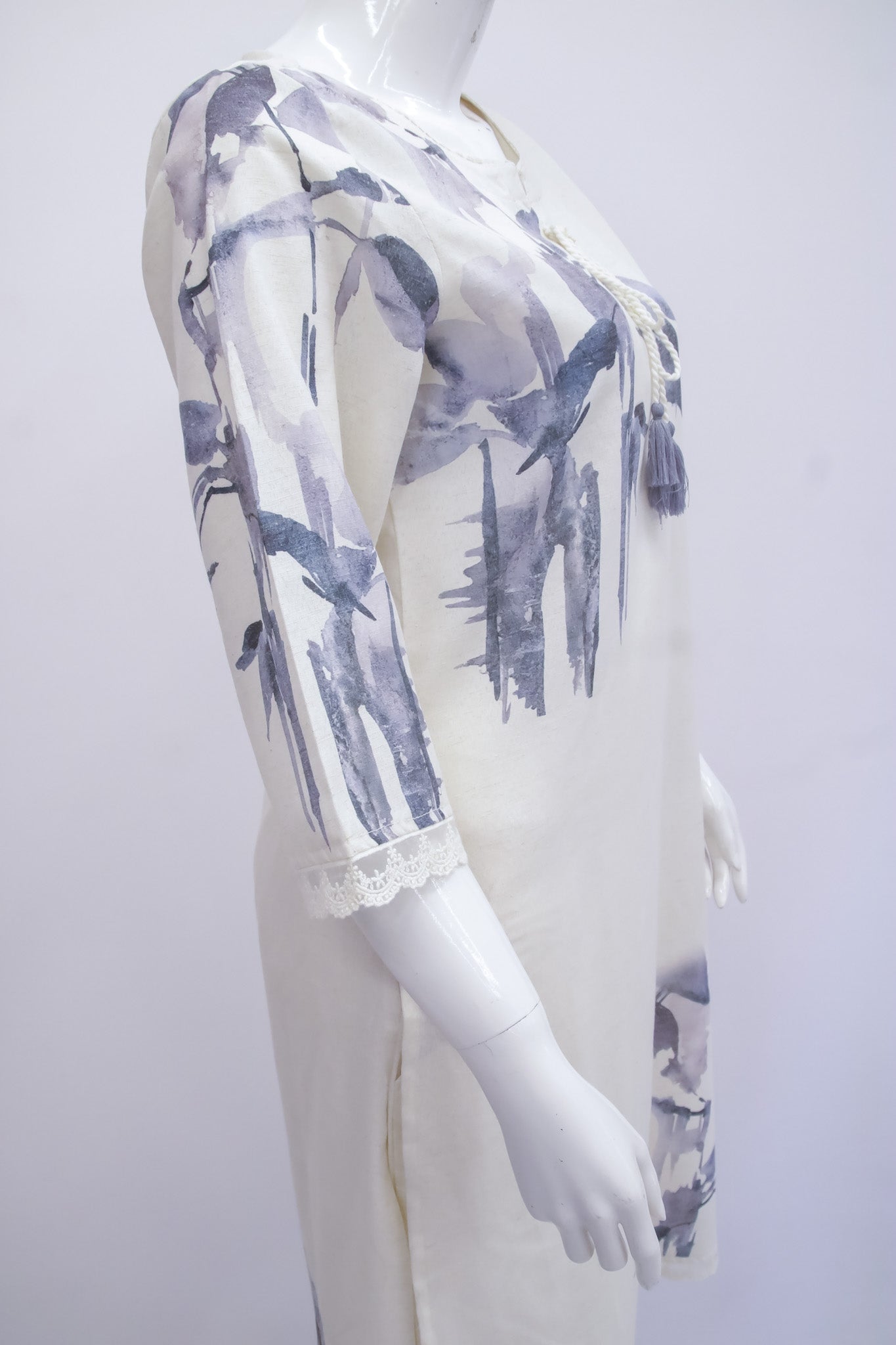 Mannequin wearing a white outfit with blue floral pattern on a plain background