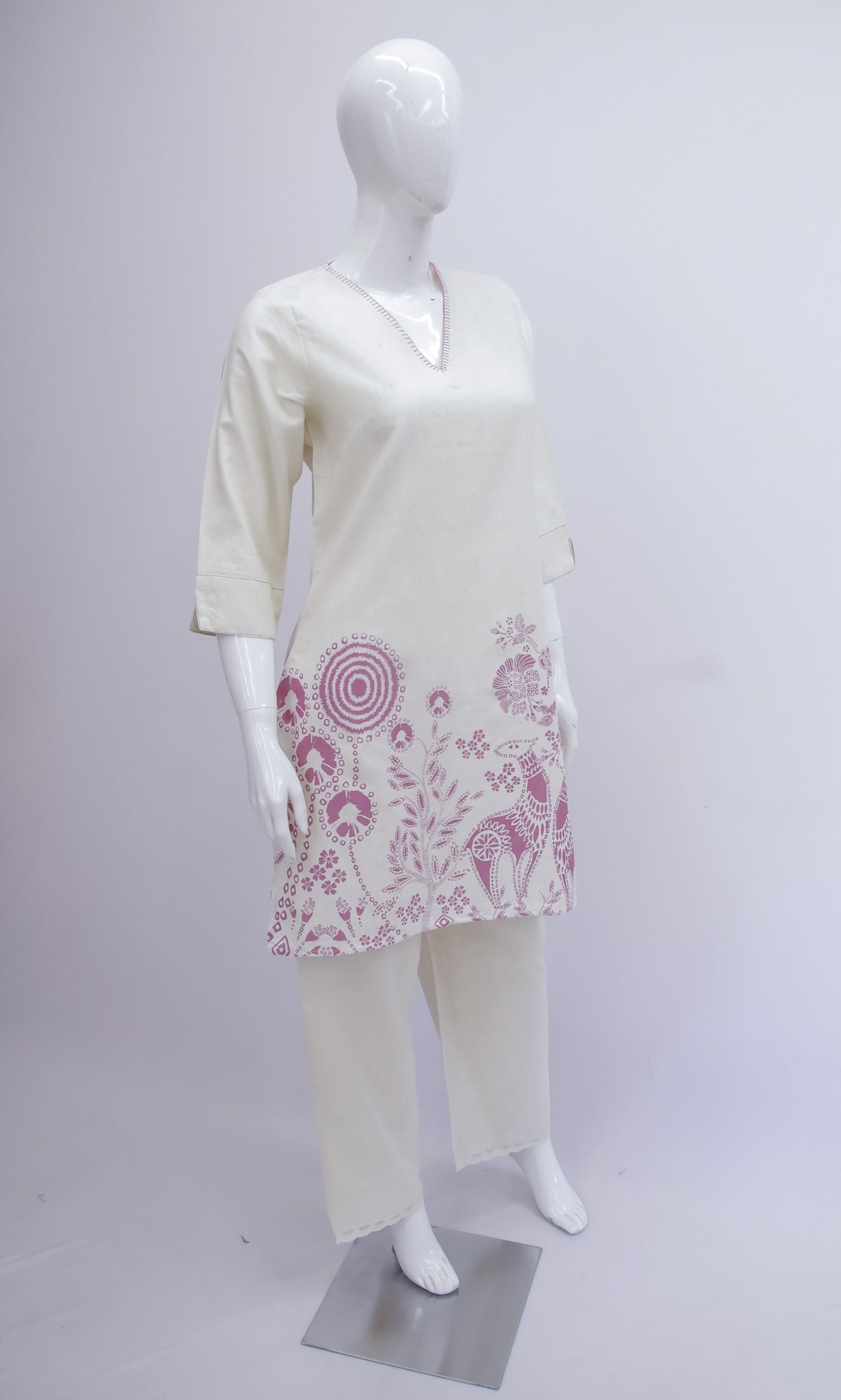 Mannequin wearing a white outfit with pink floral patterns on a plain background