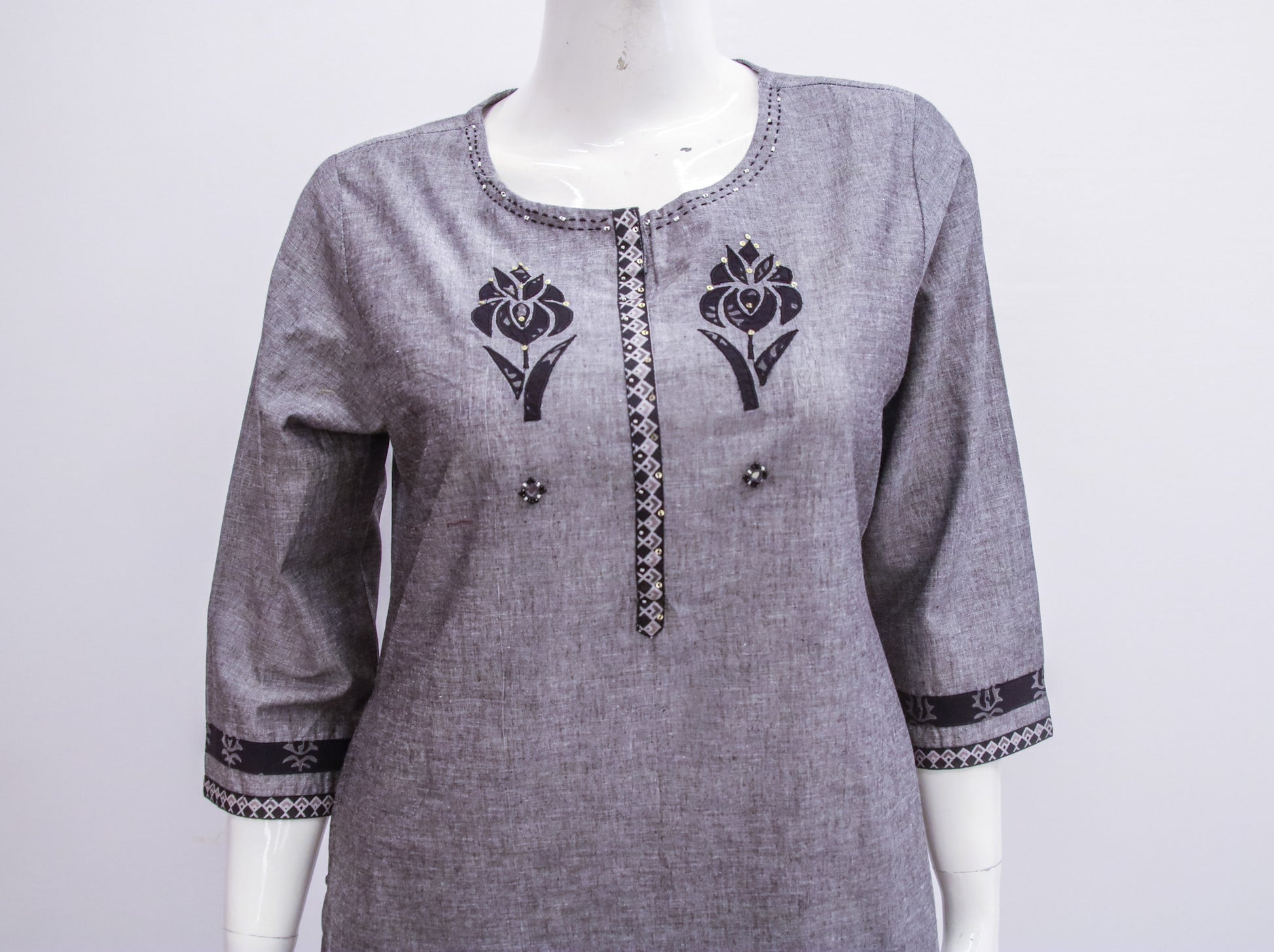 Gray kurta with black floral embroidery on a mannequin against a white background
