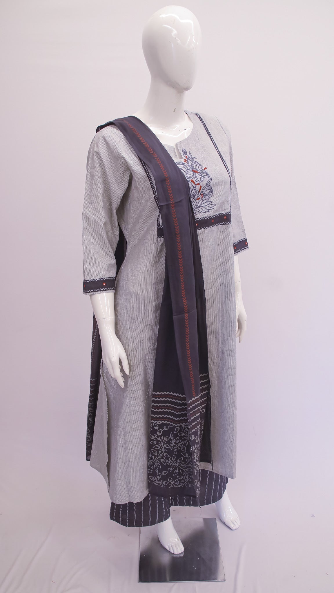 Mannequin wearing a long, light gray dress with a dark blue and red pattern on a white background