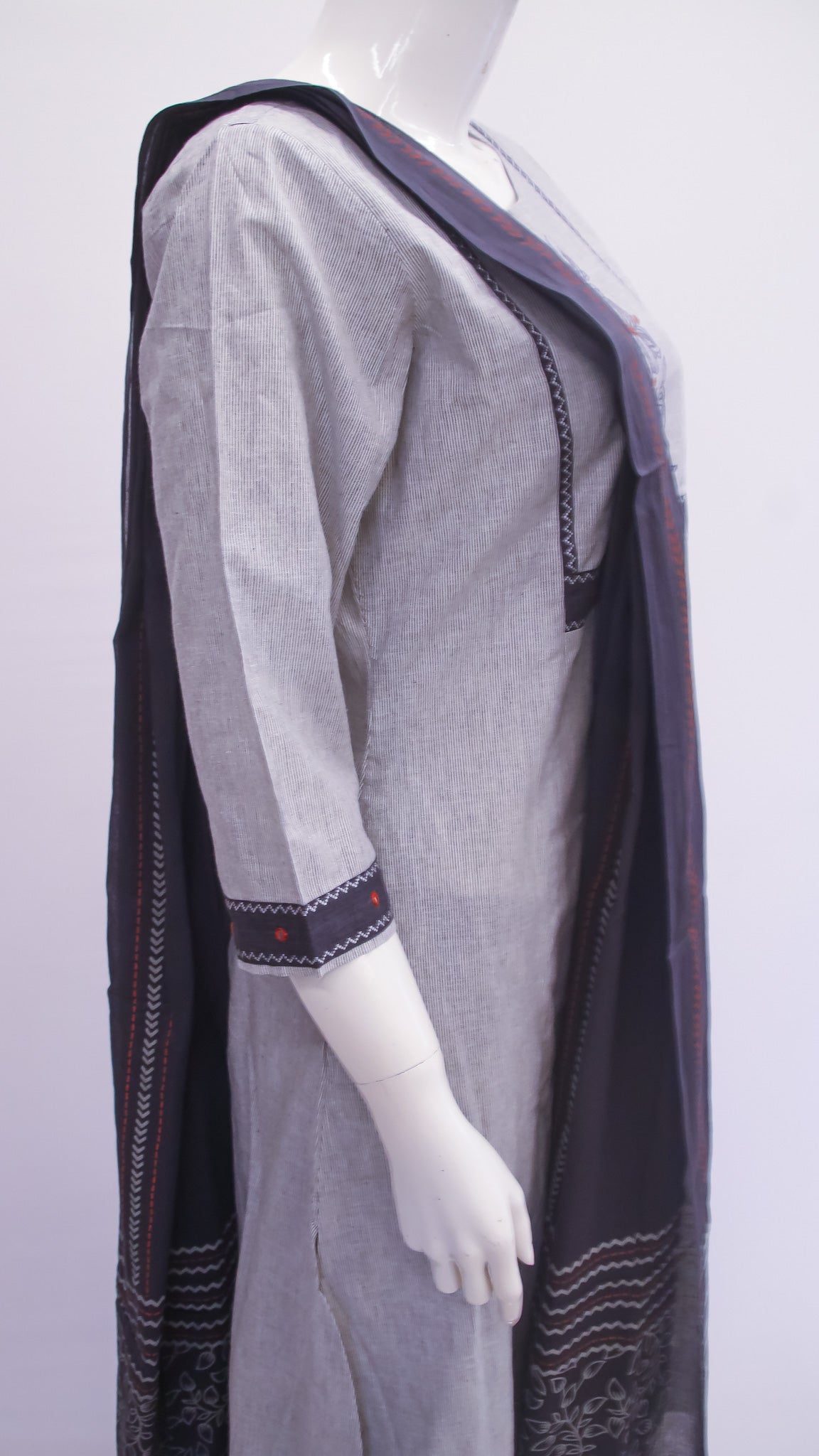 Mannequin wearing a gray dress with a black shawl on a white background