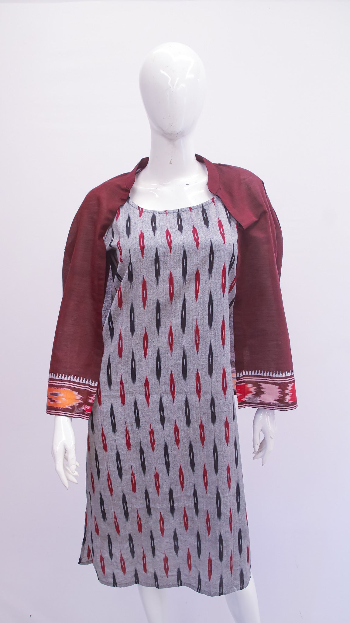 Mannequin wearing a patterned dress with a maroon jacket on a white background