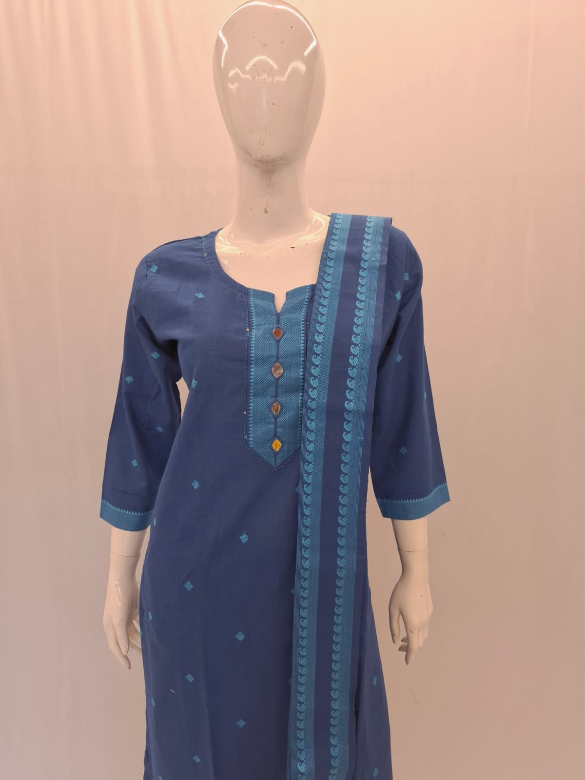 Blue dress with decorative elements on a mannequin against a beige background