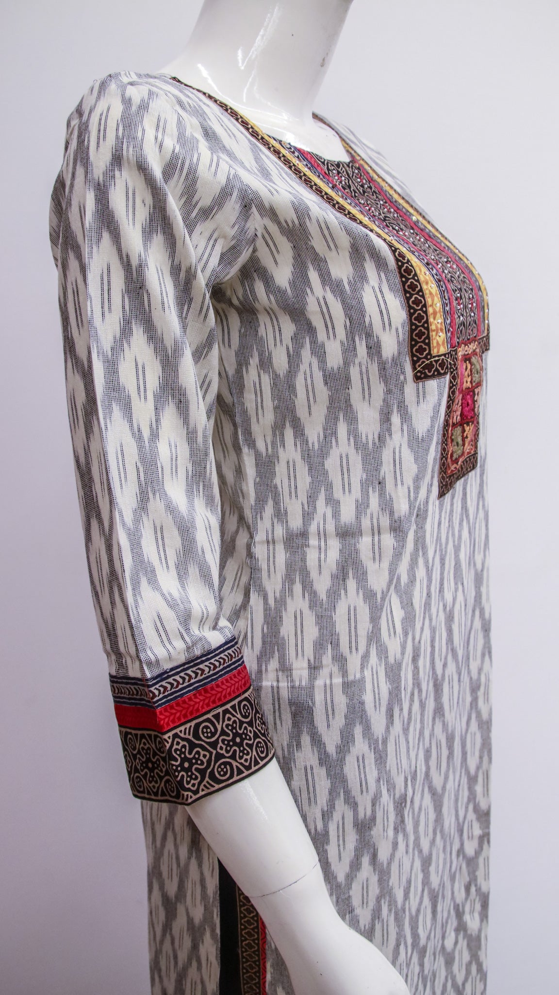 Mannequin wearing a patterned dress with intricate designs on a plain background