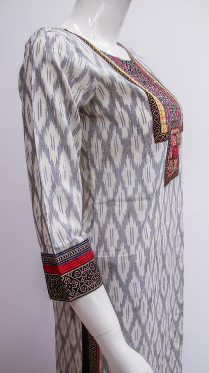 Mannequin wearing a patterned dress with intricate designs on a plain background