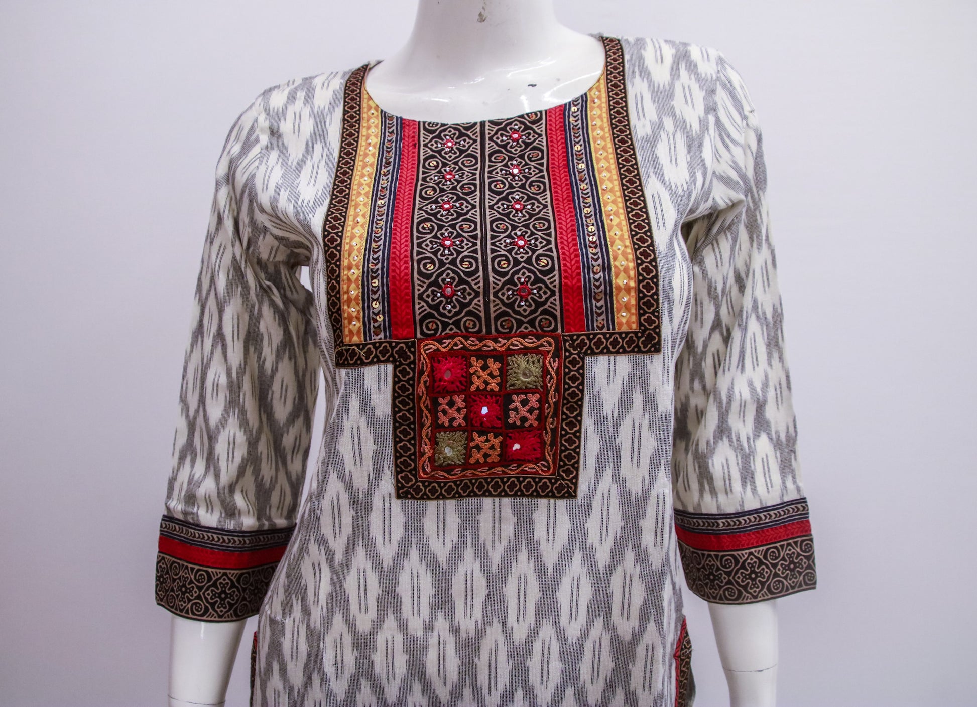 Traditional patterned top on a mannequin against a white background