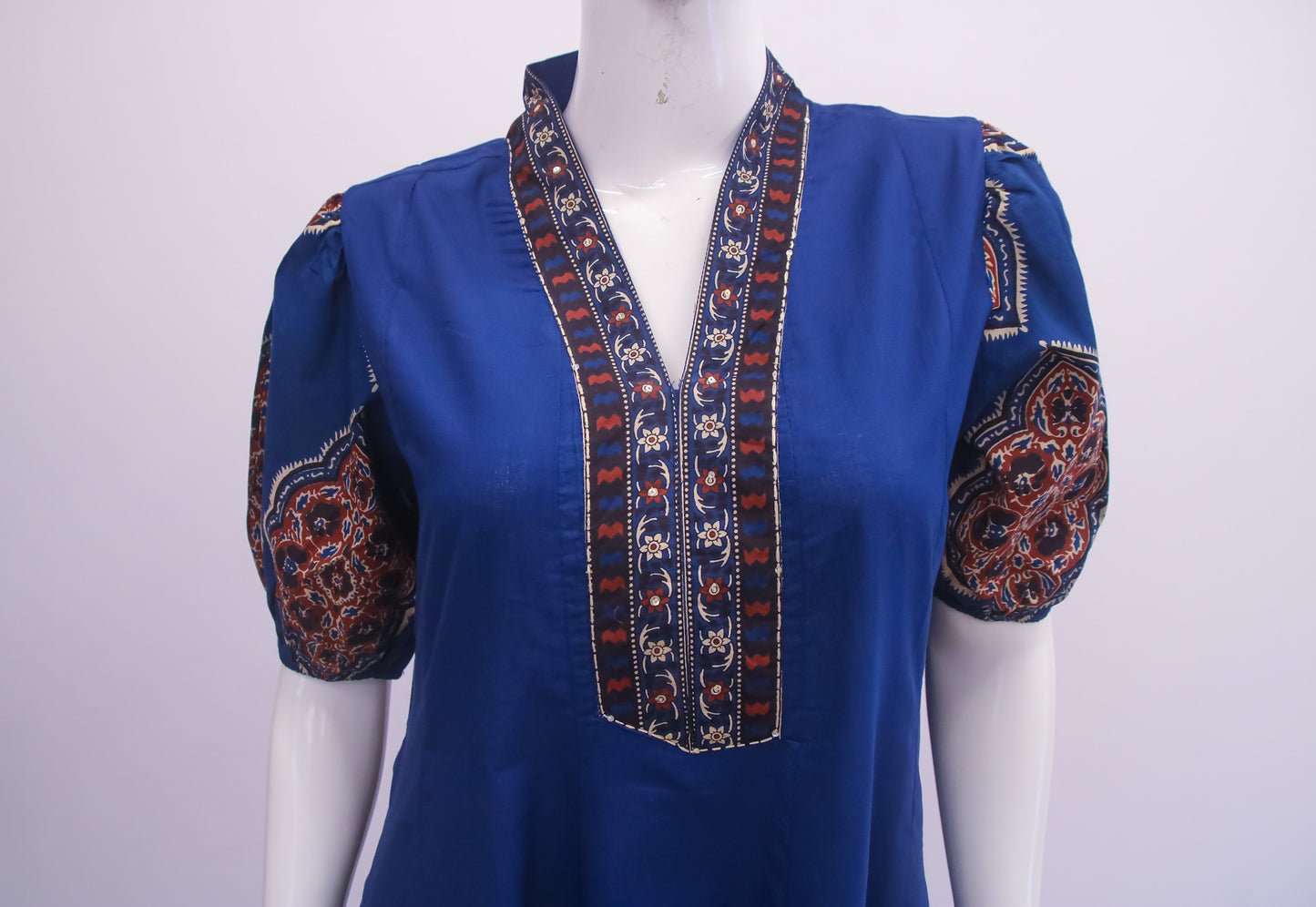 Blue blouse with intricate patterns on a mannequin against a white background