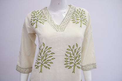 White top with green leaf patterns on a mannequin against a white background
