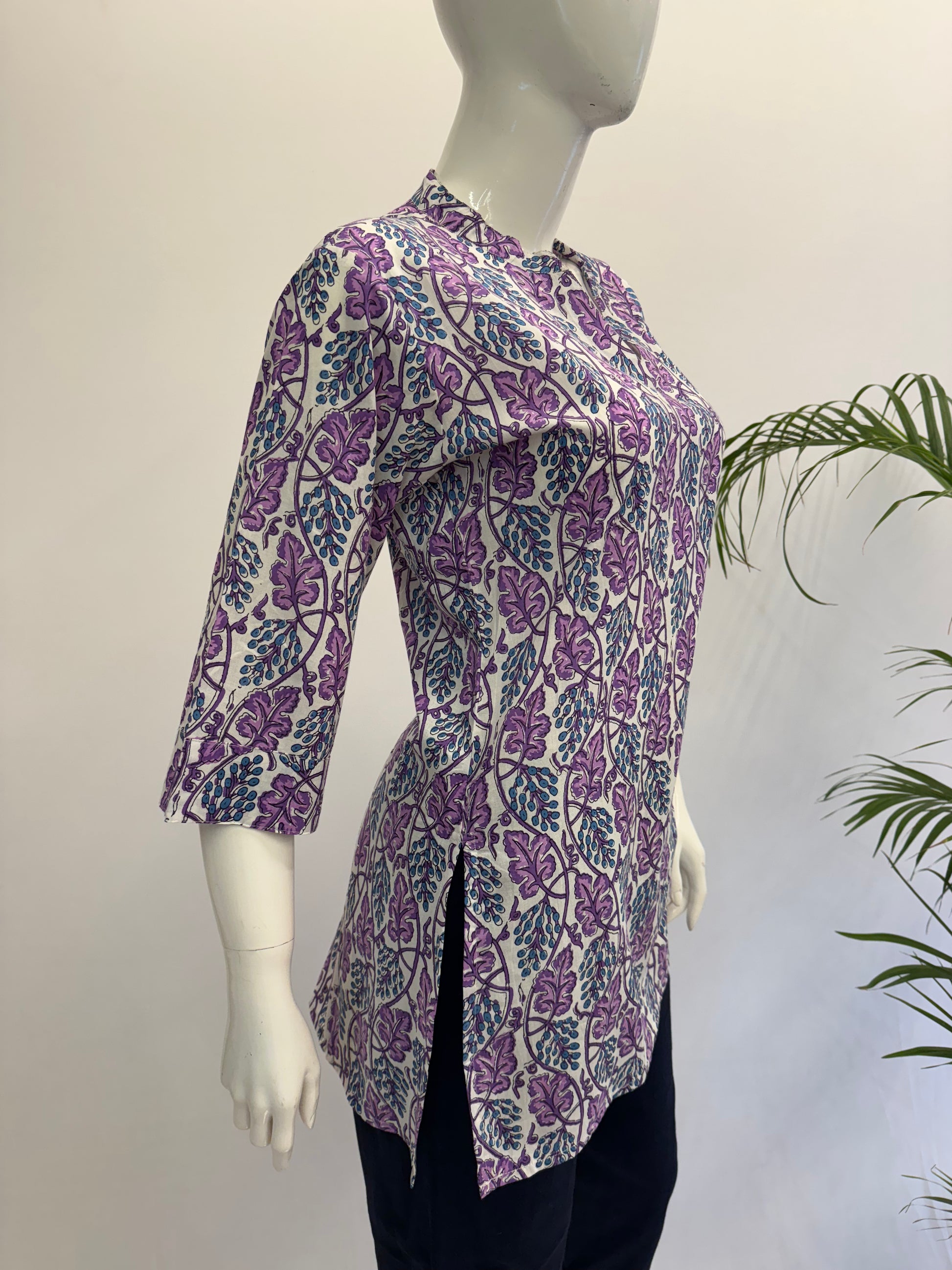 Mannequin wearing a purple floral patterned shirt with a white background