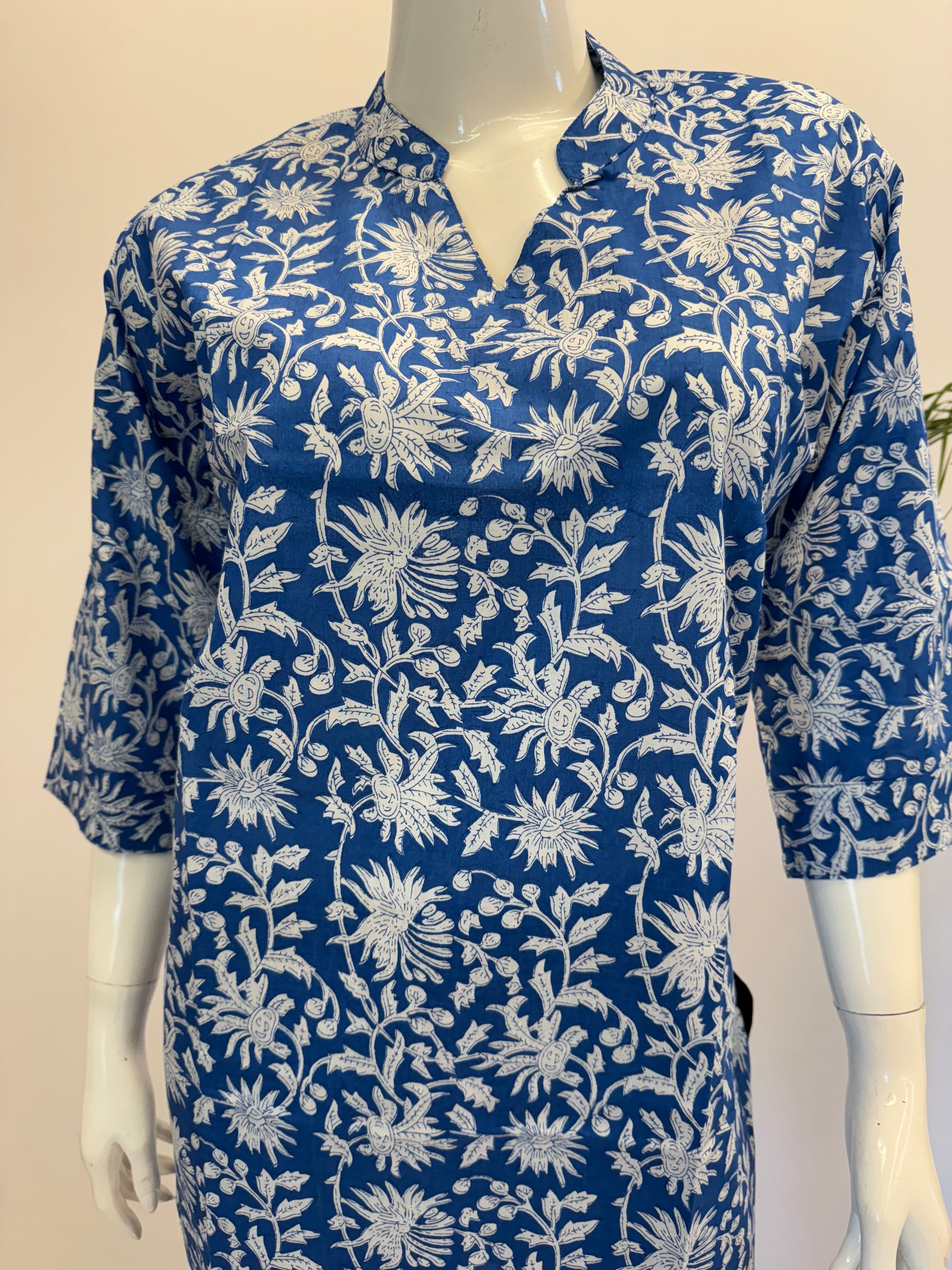 Blue dress with white floral pattern on a mannequin against a plain background