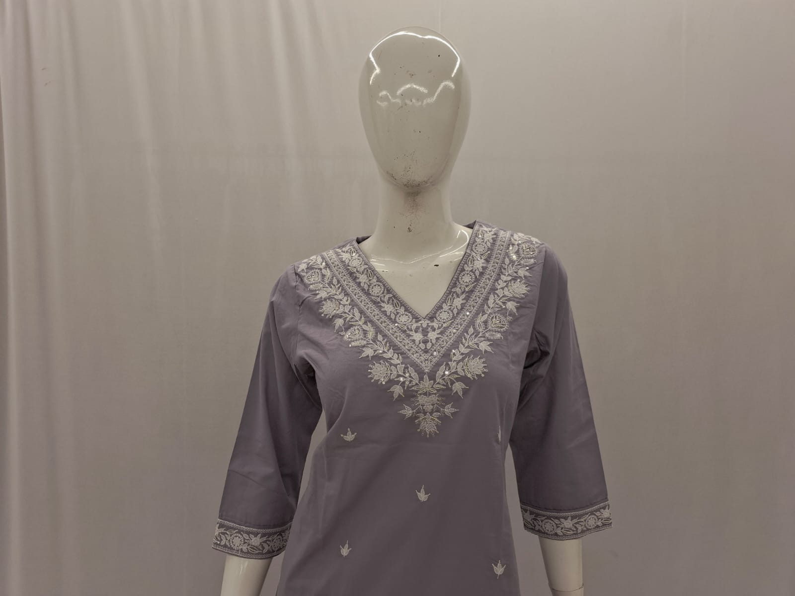Purple embroidered top on a mannequin against a plain background