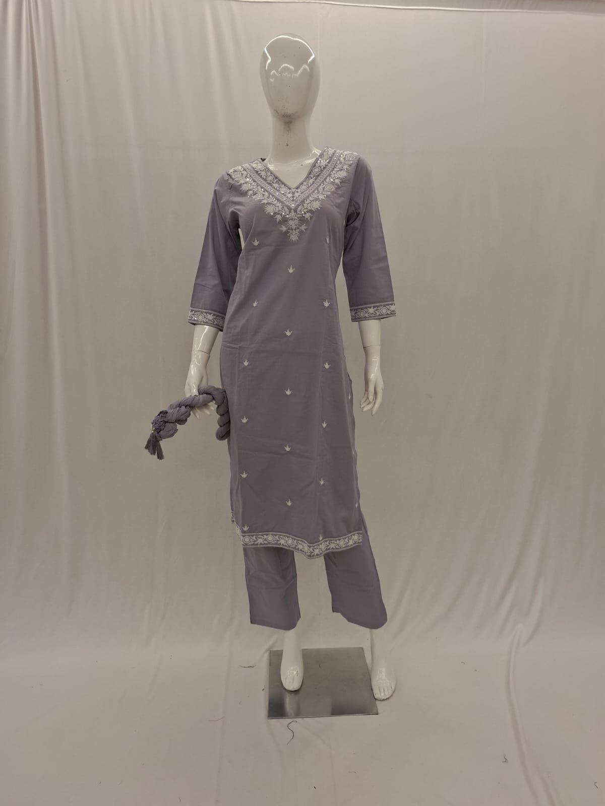 Mannequin wearing a gray traditional outfit with intricate designs on a plain background