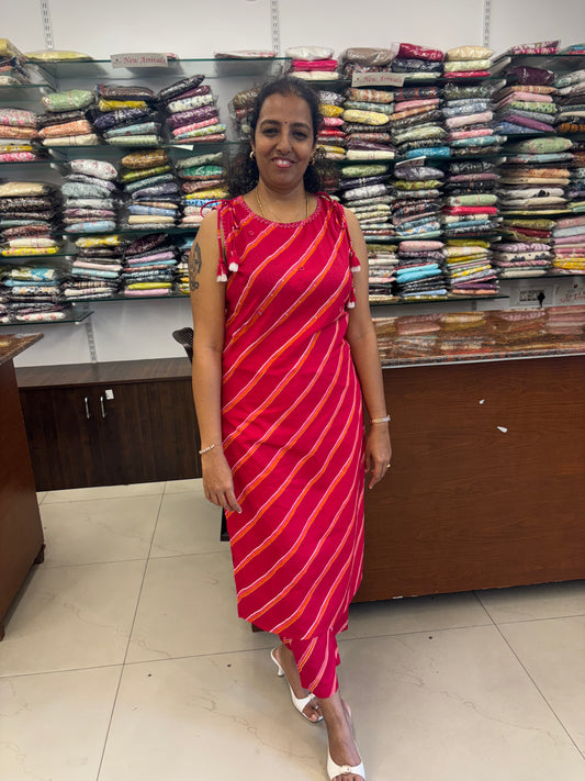 Woman holding a red and orange striped saree in front of a wall of folded clothes.