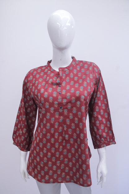Red patterned blouse on a white mannequin against a white background