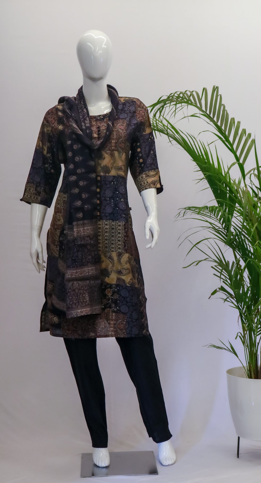 A mannequin displaying a black dupatta set with floral print, consisting of a kurta, pant, and dupatta, standing in a retail setting.