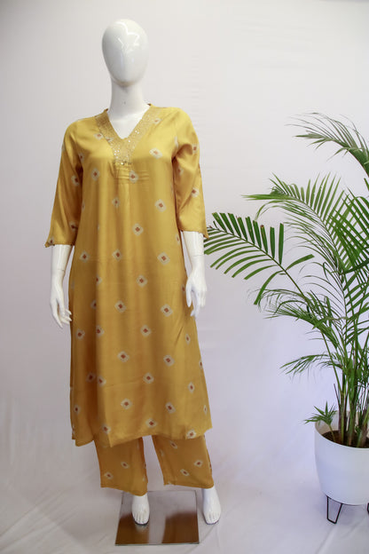 A mannequin displaying a mustard yellow top and pants set with geometric patterns and embroidery on the kurta.