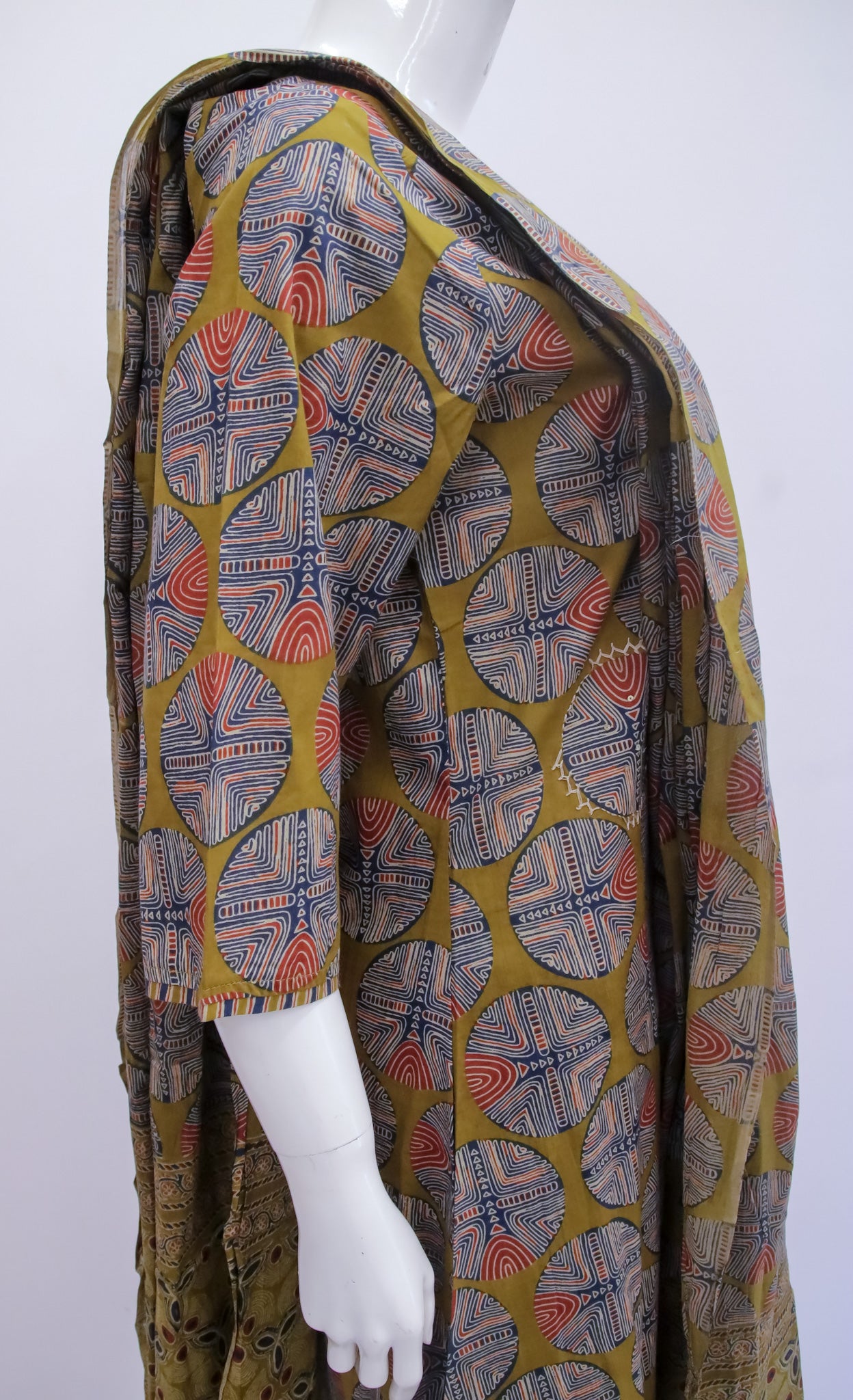 Mannequin wearing a patterned coat with a geometric design on a white background
