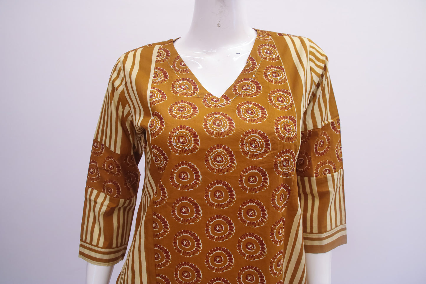 Mannequin wearing a patterned brown and beige top on a white background