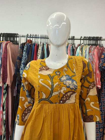 Mannequin wearing a mustard yellow dress with floral patterns in a clothing store.